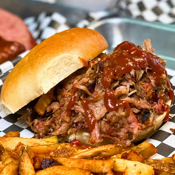 Baby Back Blues BBQ pulled pork sandwich with barbecue sauce and a side of french fries.