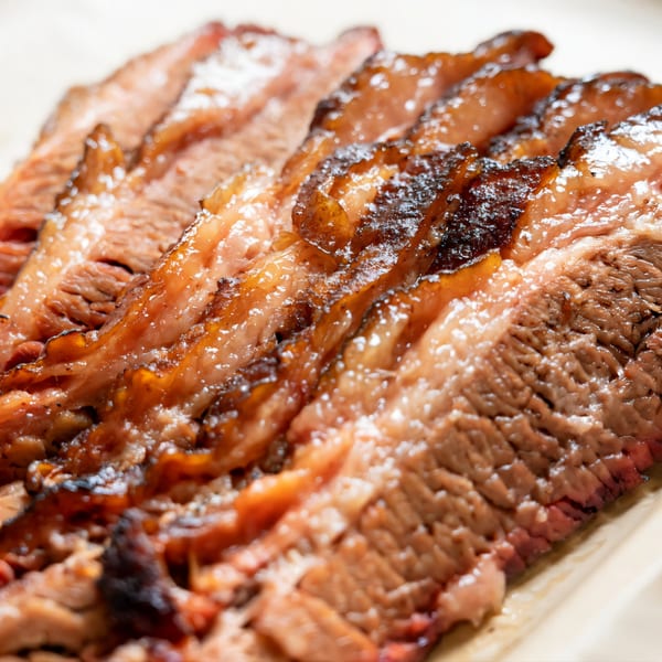 Close-up of glistening, sliced BBQ brisket with a dark, smoky crust from Baby Back Blues BBQ.