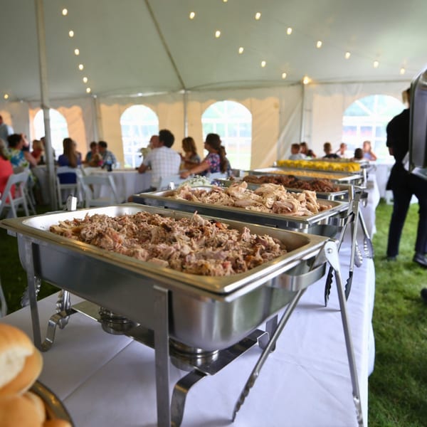 Baby Back Blues BBQ buffet with pulled pork and chicken under a tent with guests.