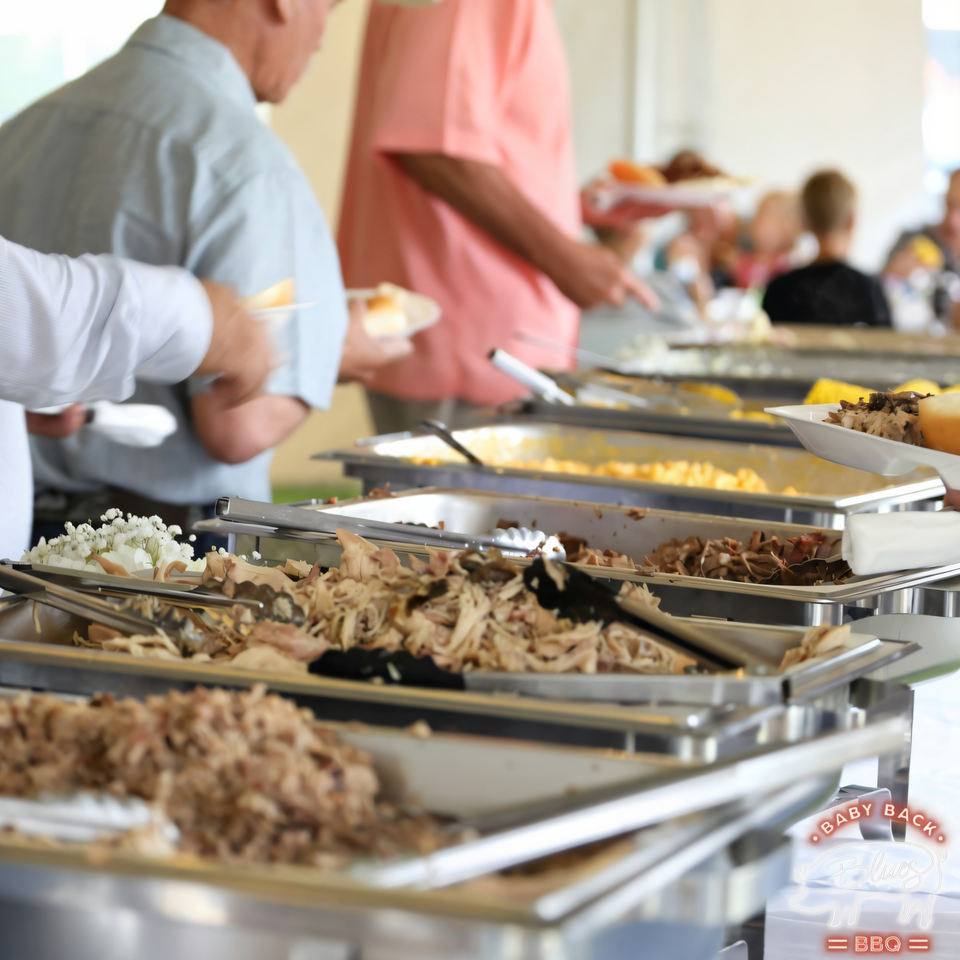 People serving themselves from a Baby Back Blues BBQ buffet line with pulled pork and sides.